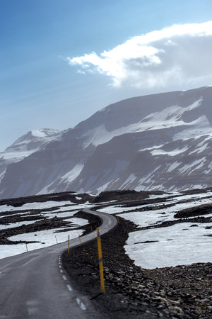A mesmerizing view of snow-covered roads winding through Icelandic mountains, surrounded by icy peaks and Arctic wildernessの写真素材