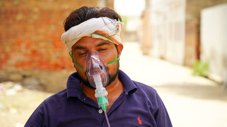 Jaipur, India - May 21: Close up sick Yong boy with face oxygen mask with liquid Oxygen flow outside of hospital. Boy infected with Covid 19 disease. COVID 19 concept.のeditorial素材