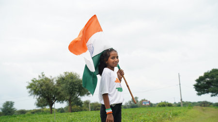 Indian student or children holding or waving Tricolour with greenery in the background, celebrating Independence or Republic day. Har Ghar Tirangaの写真素材
