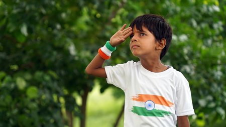 Little boy wearing indian tricolor Tshirt, face painted with triclolor and saluting. Celebrating...
