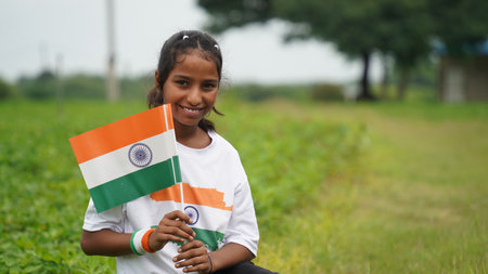 Indian student or children holding or waving Tricolour with greenery in the background, celebrating Independence or Republic day. Har Ghar Tirangaの写真素材
