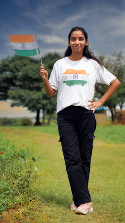 Cute Indian girl holding Indian flag in her hand and smiling. Celebrating Independence day or Republic day in India. A girl showing pride of Tiranga. Har Ghar Tirangaの写真素材