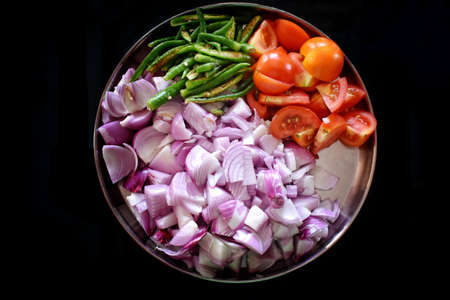 Heaps of different cut vegetables isolated on black background as package design element. Top view.の写真素材