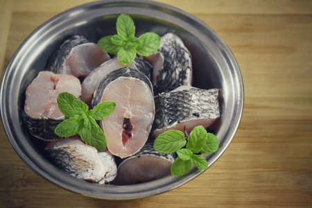 Raw fish fillet of tilapia on a cutting Board with lemon and spices on a steel bowl. cutting board with copy space, india.の写真素材