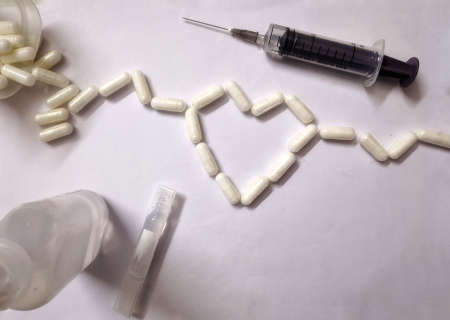 Hyderabad India - March 10, 2021: Assorted pharmaceutical medicine pills, tablets and capsules for the treatment of heart disease. Heart shape and bottle of pills. Copy space for textの写真素材