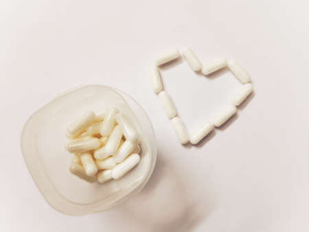 Vitamins in the form of a Heart from a jar on a blue background. Supplement for Vitamins and Mineralo, Potassium Magnesium for the treatment of the cardiovascular system. Top view, top viewの写真素材