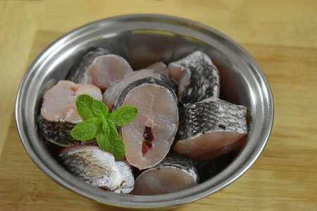 Raw fish fillet of tilapia on a cutting Board with lemon and spices on a steel bowl. cutting board with copy space, india.の写真素材