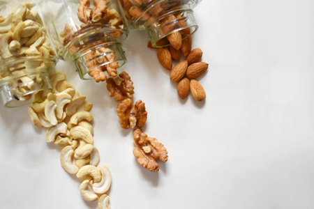 side view of various dried fruit slices scattered from glass jars on black background