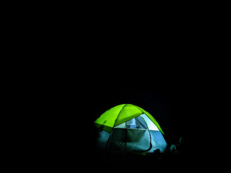 Glowing tent in the mountains under a starry skyの写真素材