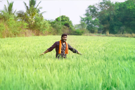Happy indian farmer in wheat field