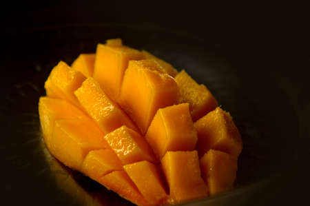 Mango slice cut to cubes close-up isolated on black backgroundの写真素材