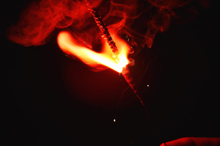 Burning incense stick on black background, closeup of photo