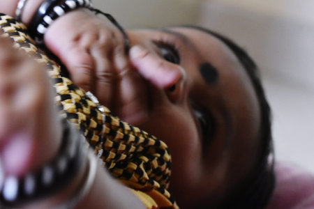 A baby in the arms of his mother. Shallow depth of field.