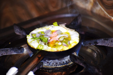 fried eggs with vegetables on a gas stove in the kitchen of the restaurantの写真素材