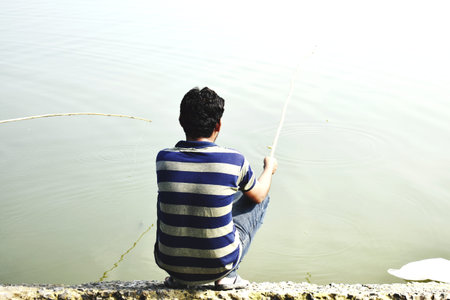 fisherman sitting on the bank of the river and fishing.