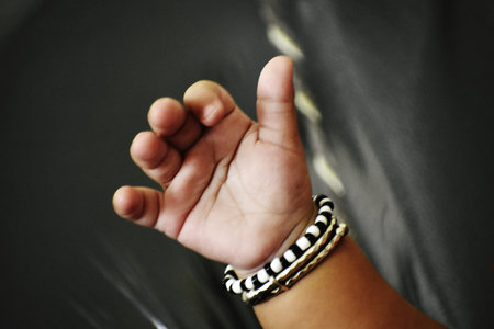 hand of a young man with a bracelet on his wrist, black background