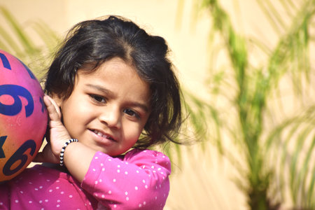 Little girl playing with a ball in her hand on a sunny dayの写真素材
