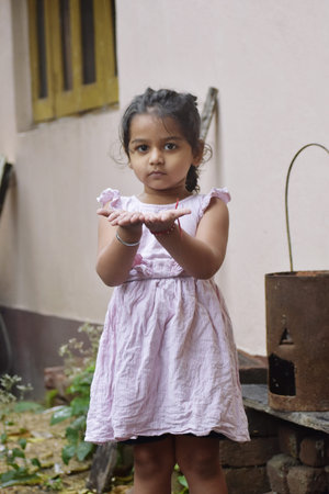 Little girl in a pink dress with her hands folded in prayer.