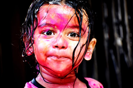 Baby girl with face painted in colors of Holi festival in India