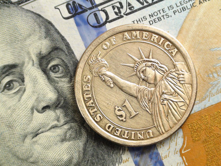 Macro view of coin depicting a statue of liberty against a background of dollar bills