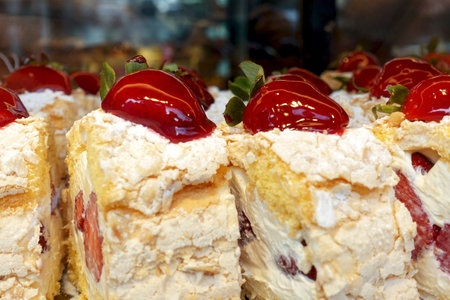 Pieces of delicious cake with cream and strawberries.