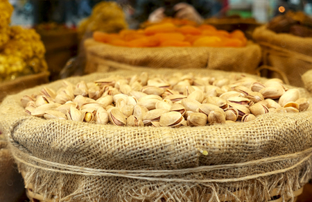 Pistachios in a bowl with burlap on the counter. Sale of nuts and dried fruits on the market.の写真素材