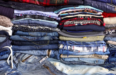 Stacks of denim and other colored clothes as a background.