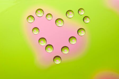Water drops in the form of heart on a multi-coloured celebratory backgroundの写真素材