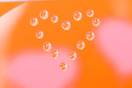 Water drops in the form of heart on a multi-coloured celebratory backgroundの写真素材