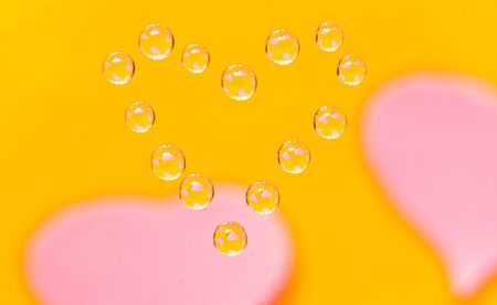 Water drops in the form of heart on a multi-coloured celebratory backgroundの写真素材