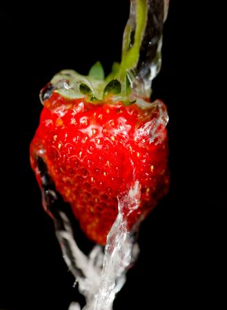 strawberry under the stream of water on a dark backgroundの写真素材