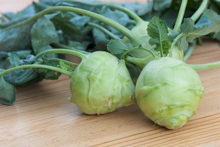 fresh cabbage kohlrabi with leaves on a wooden tableの写真素材
