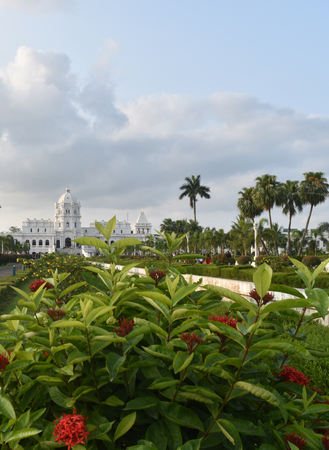 red flowers in front white Indian palace closeup cloudy sky landscape Ujjayanta Palace in Agartala Tripuraのeditorial素材