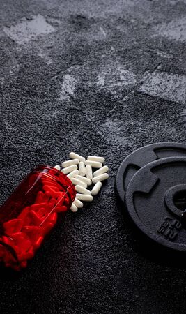 Sports supplements with weights on dark background. Medicinesの写真素材