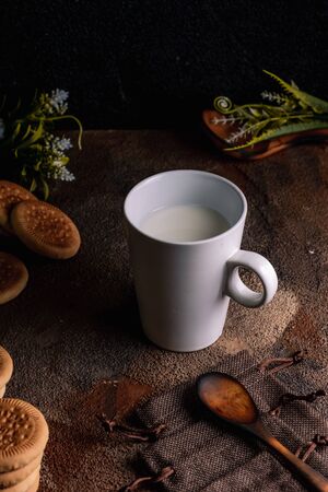 Fresh milk with homemade cookies on a wooden table, dark background.の写真素材