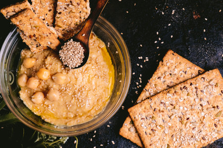 Chickpea hummus with sesame in glass bowl on wooden table. Vegan food