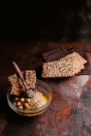 Chickpea hummus with sesame in glass bowl on wooden table. Vegan foodの写真素材