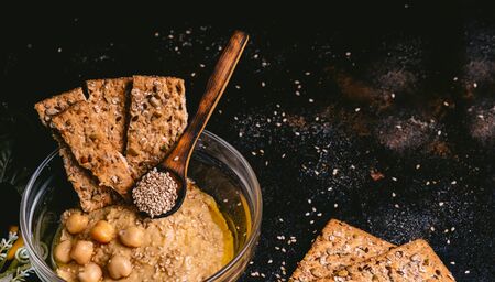 Chickpea hummus with sesame in glass bowl on wooden table. Vegan foodの写真素材