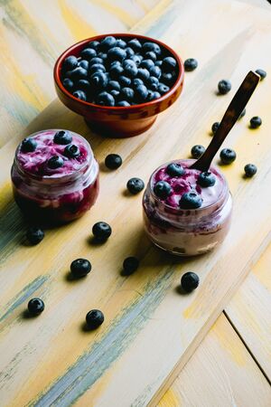 Homemade blueberry yogurt in glass bowls, healthy breakfast, selective focus. Old wood backgroundの写真素材