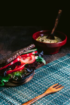 Vegetable sandwich with tomato, lettuce, zucchini, cucumber and more vegetables. Dark background. Vegan foodの写真素材