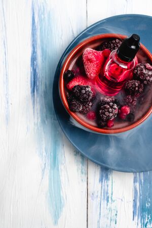 Vaping concept. Eliquid of berries. Strawberry, blueberry, raspberry concentrateの写真素材