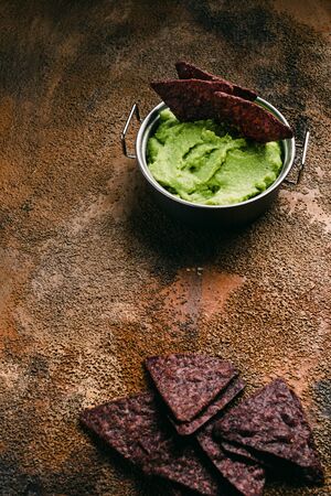 Bowl guacamole and nachos on wooden background. Top viewの写真素材