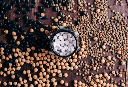 legumes vitamins, vitamin pills on wooden table with chickpeas, lentils and beansの写真素材