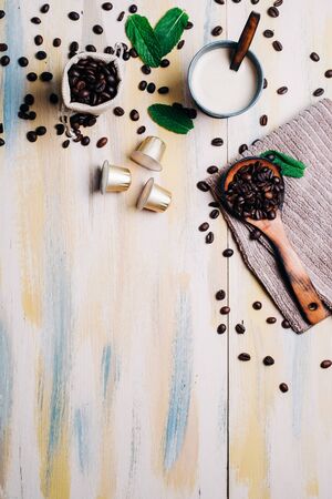 Coffee beans on vintage light wooden table, with coffee capsule and a cup of coffee. Top view. Copyspace.の写真素材