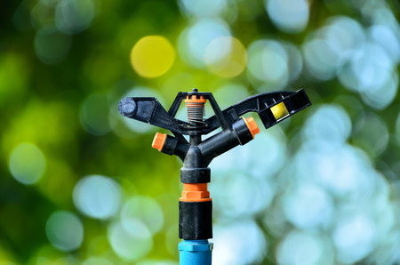 sprinklers watering on sunny green nature backgroundの写真素材