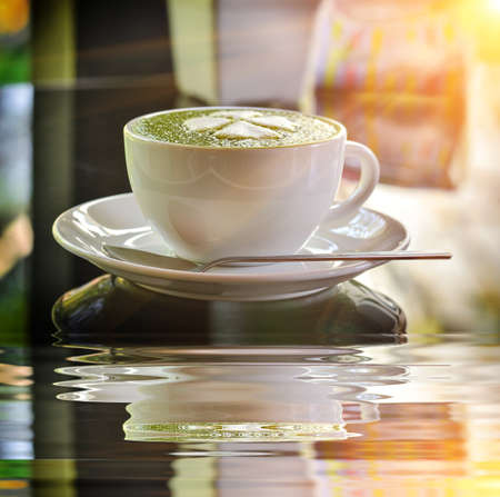 Hot green tea latte with matcha powder in morning lightの写真素材