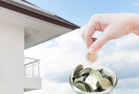 woman hand putting a coin on ,saving ,Donation Investment ,Coins in hands money Savings and apartment ,condominium,house,homeの写真素材
