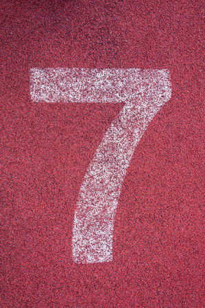 Number seven on running track. White track number on red rubber racetrack, texture of running racetracks in stadiumの写真素材