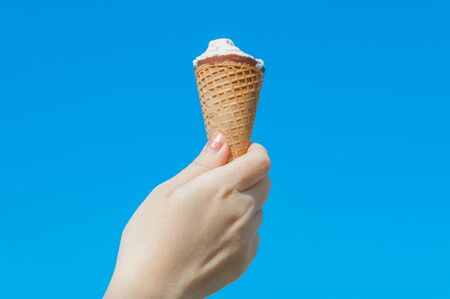 Woman hand holding  icecream on blue skyの写真素材