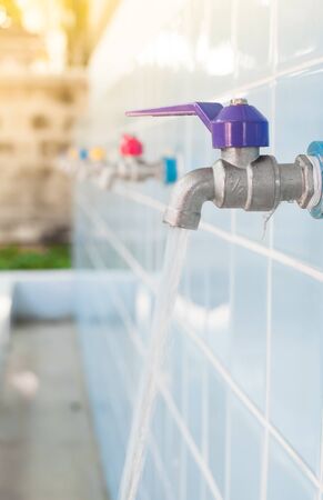 Open faucet Colorful Faucet on a blue wallの写真素材